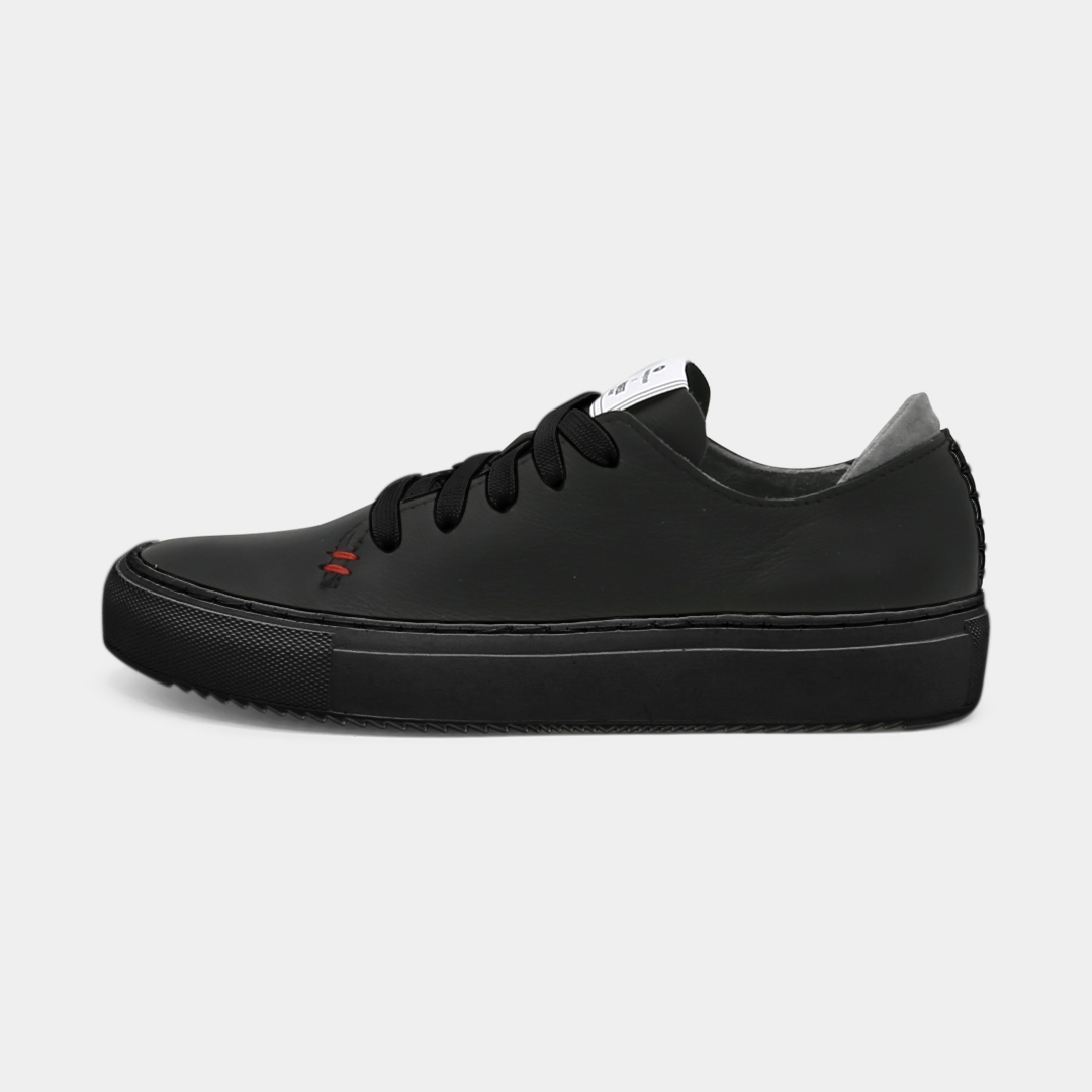 A black colored low-top sneaker with a black sole and laces, lateral view.