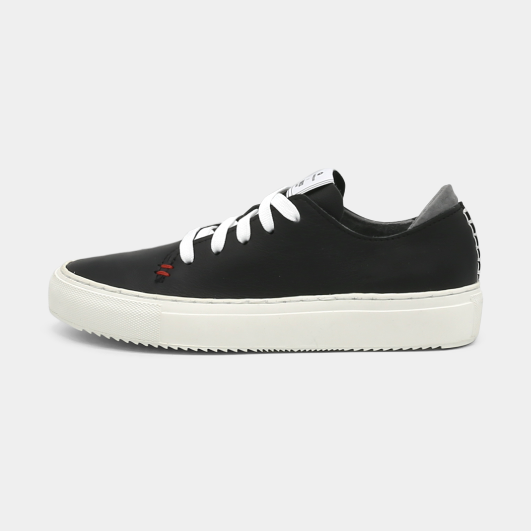 A black colored low-top sneaker with a white sole and laces, lateral view.