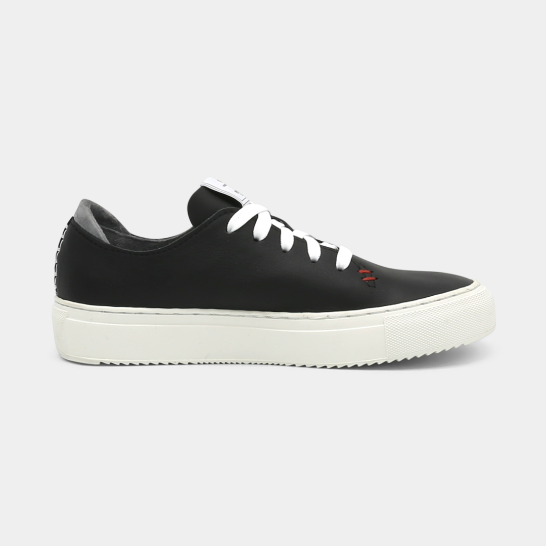 A black colored low-top sneaker with a white sole and laces, medial view.