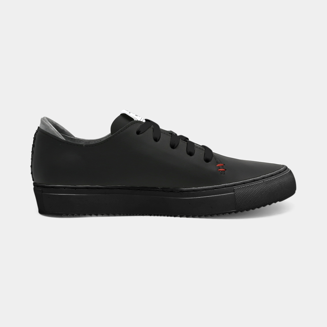 A black colored low-top sneaker with a black sole and laces, medial view.