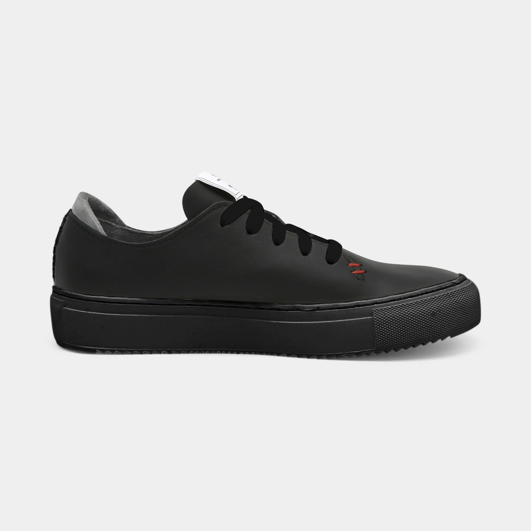 A black colored low-top sneaker with a black sole and laces, medial view.
