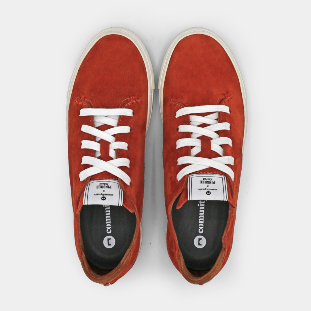 A rust colored low-top sneaker with a white sole and laces, top view.