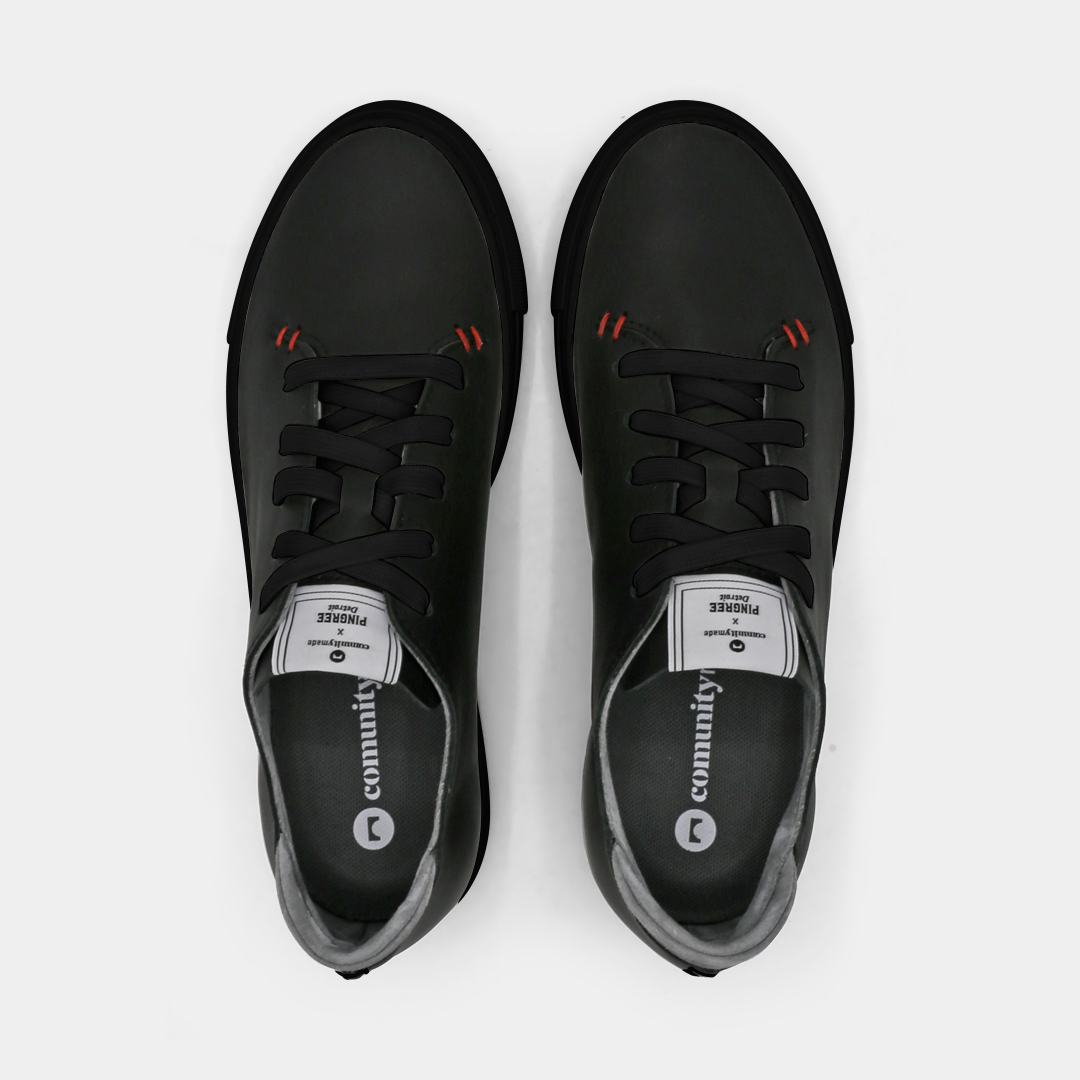 A black colored low-top sneaker with a black sole and laces, top view.