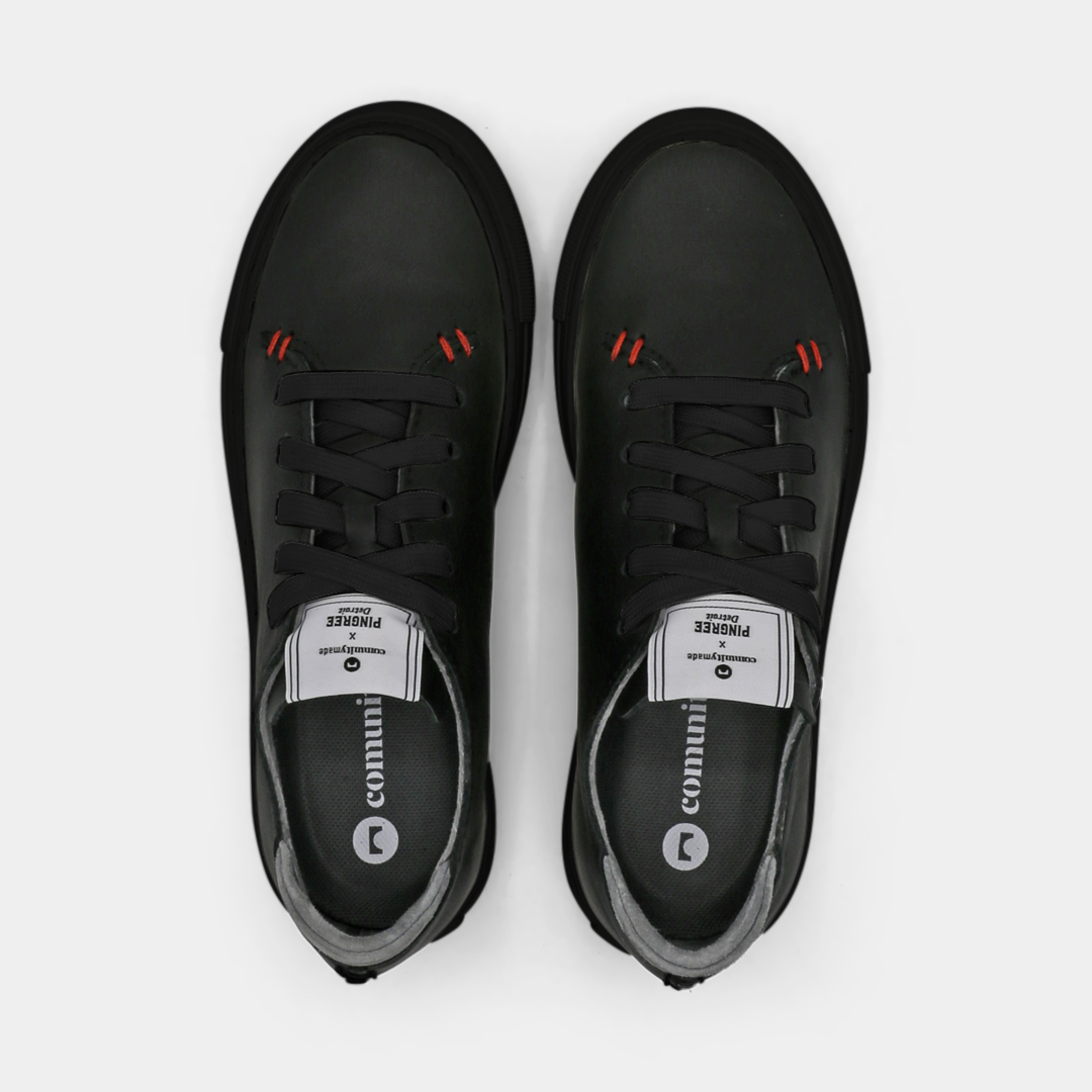 A black colored low-top sneaker with a black sole and laces, top view.