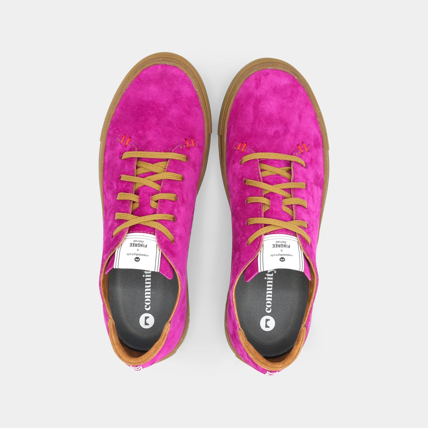 A pink low-top sneaker with a brown sole and laces, top view.