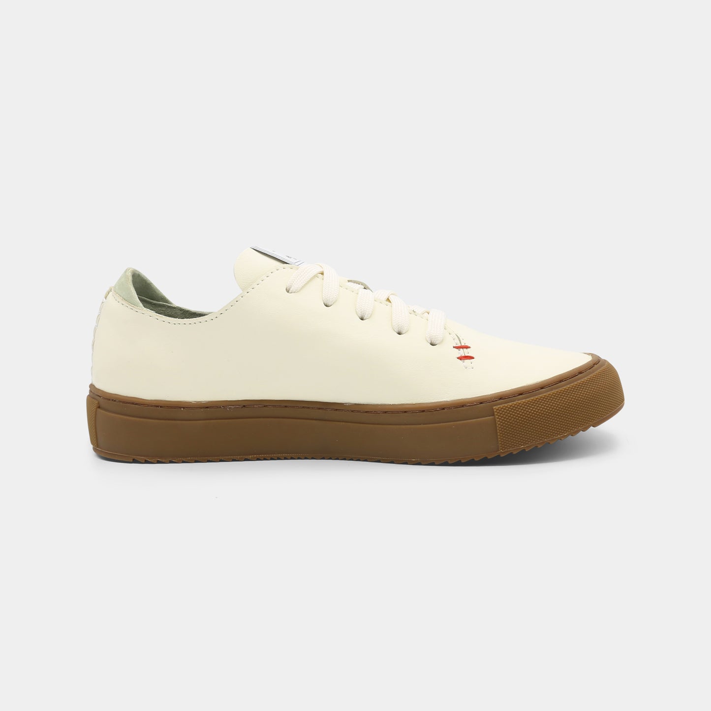 A latte colored low-top sneaker with a brown sole and white laces, medial view.