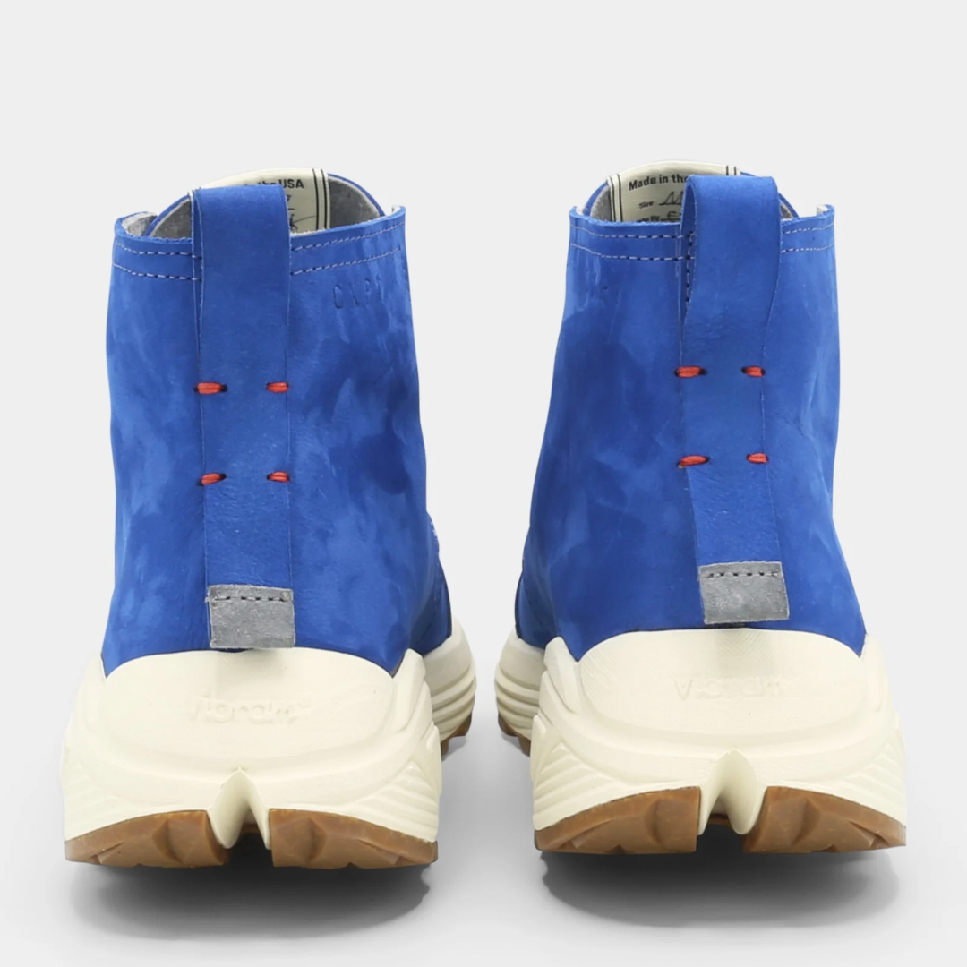 A blue high-top urban utility chukka boot with white laces and a chunky white sole back view.