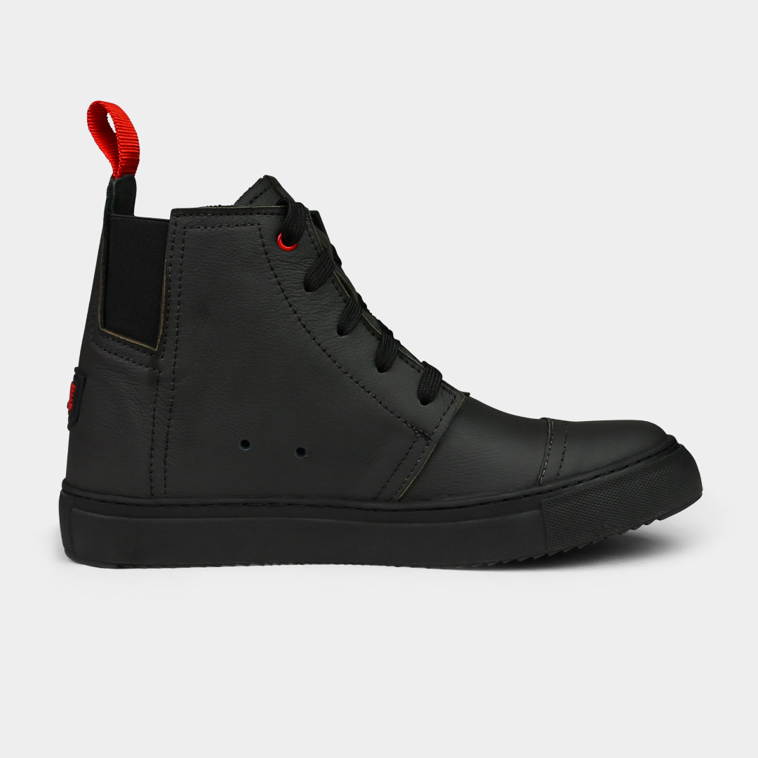 A side-angle product shot of a pair of black high-top shoes, placed side-by-side. The shoes are made of black leather, with black laces and a thick black sole. A bright red loop is attached to the back of each heel. The shoes have a sleek, modern design, and they are on a solid light gray background.