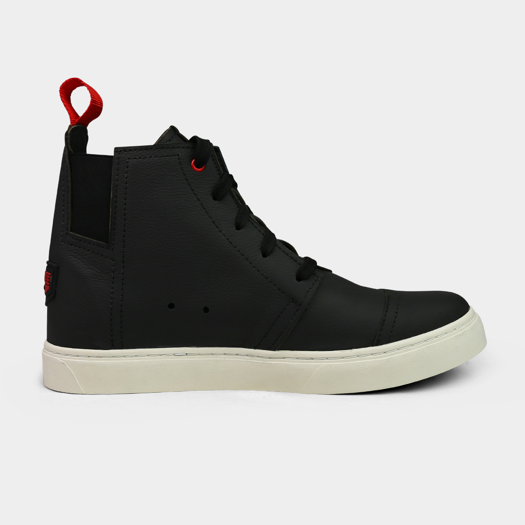 A product shot of the side of a pair of black high-top shoes. The shoes are made of black leather, with a white sole and a red loop on the back of the ankle. A red square with