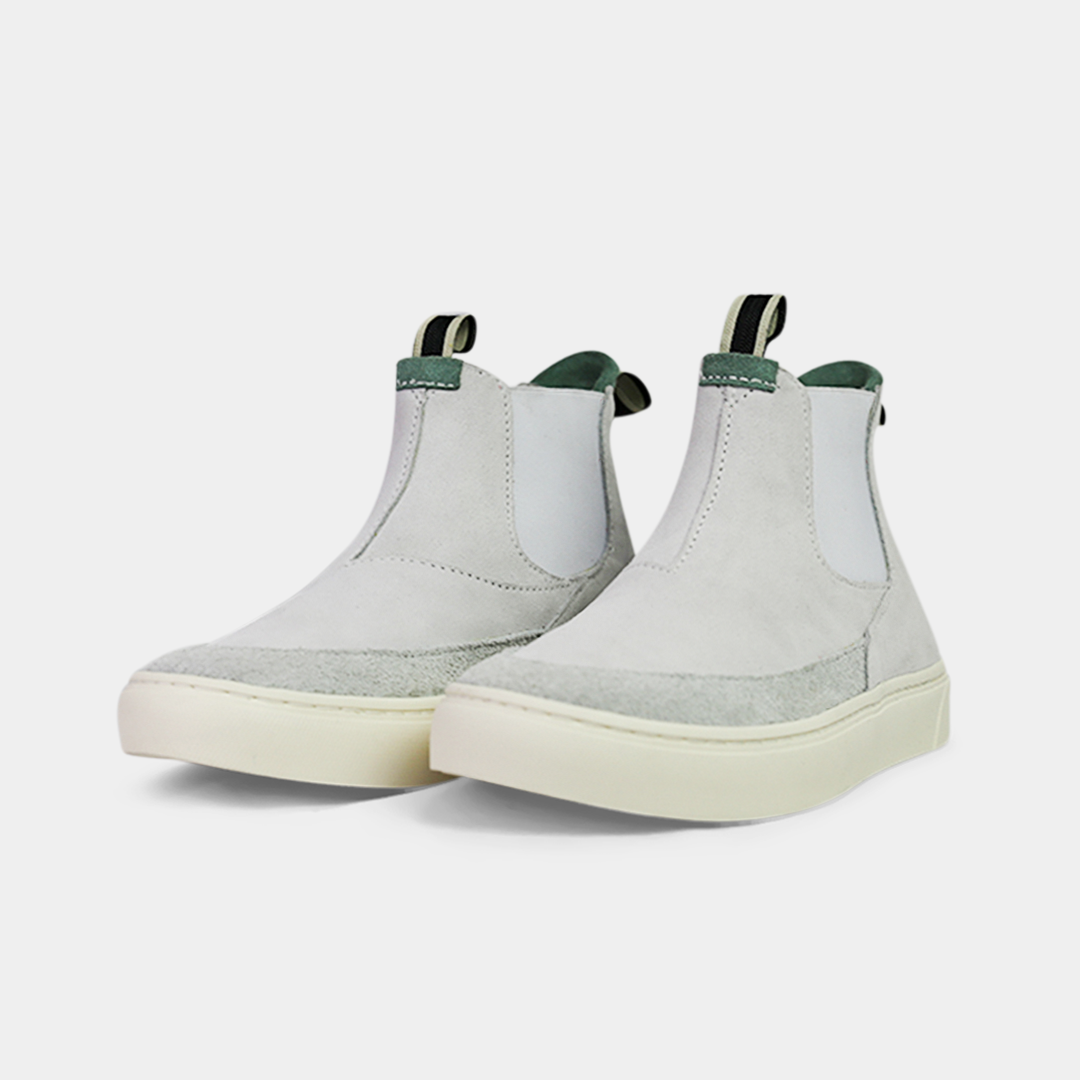 A pair of light gray suede boots with white soles. The boots feature a mint green elasticated panel and a striped brown and black pull tab at the back of the ankle. The toe area is a different texture of suede with a visible seam.
