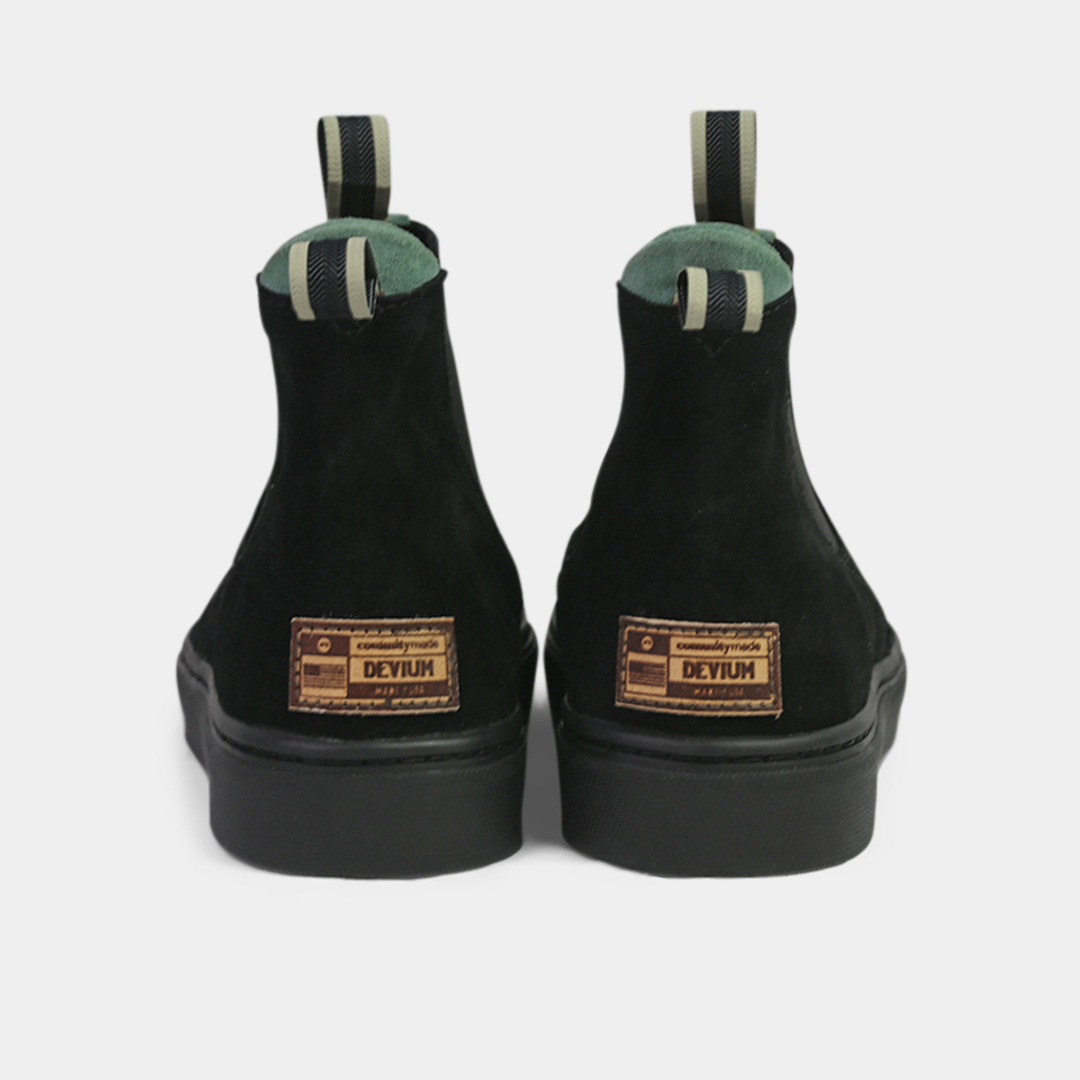 A pair of black ankle boots with a small leather logo tag on the back of each heel. The boots have a green elasticated panel and a striped brown and black pull tab at the back of the ankle.