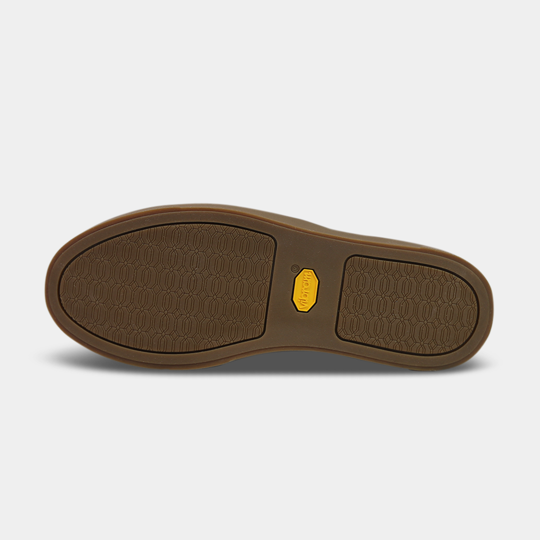 The bottom of a shoe with a brown rubber sole. The front and back of the sole have a repeating, circular pattern for grip, with a bright yellow oval logo in the center.