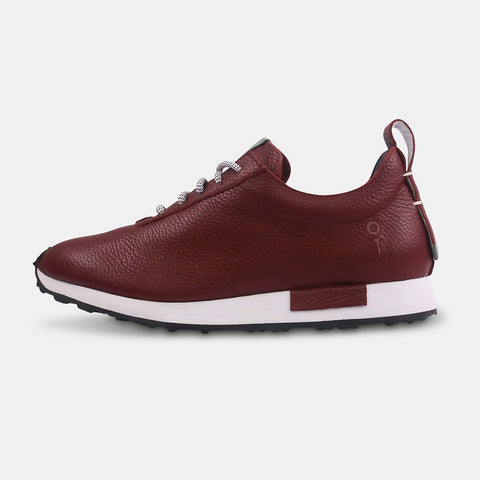 Side shot, A pair of burgundy-colored leather golf sneakers with white soles and black laces with white flecks. The shoes have a small mint green accent on the tongue and a burgundy leather pull tab on the back.